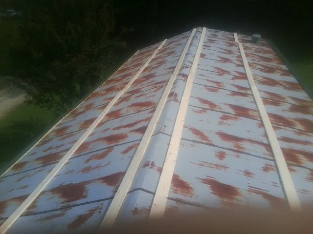 Rusted metal roof panels with new wood purlins before replacement — Storm Damage Roof Repair in Sturtevant by Roofing Brothers