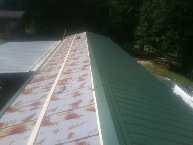 Old rusted panels beside newly installed green metal roofing — Wind Damage Roof Repair by Roofing Brothers in Sturtevant