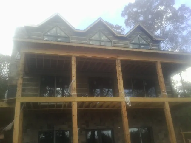 Dormers and porch framing on a large log home under construction — Roof Coating work by our crew in Sturtevant