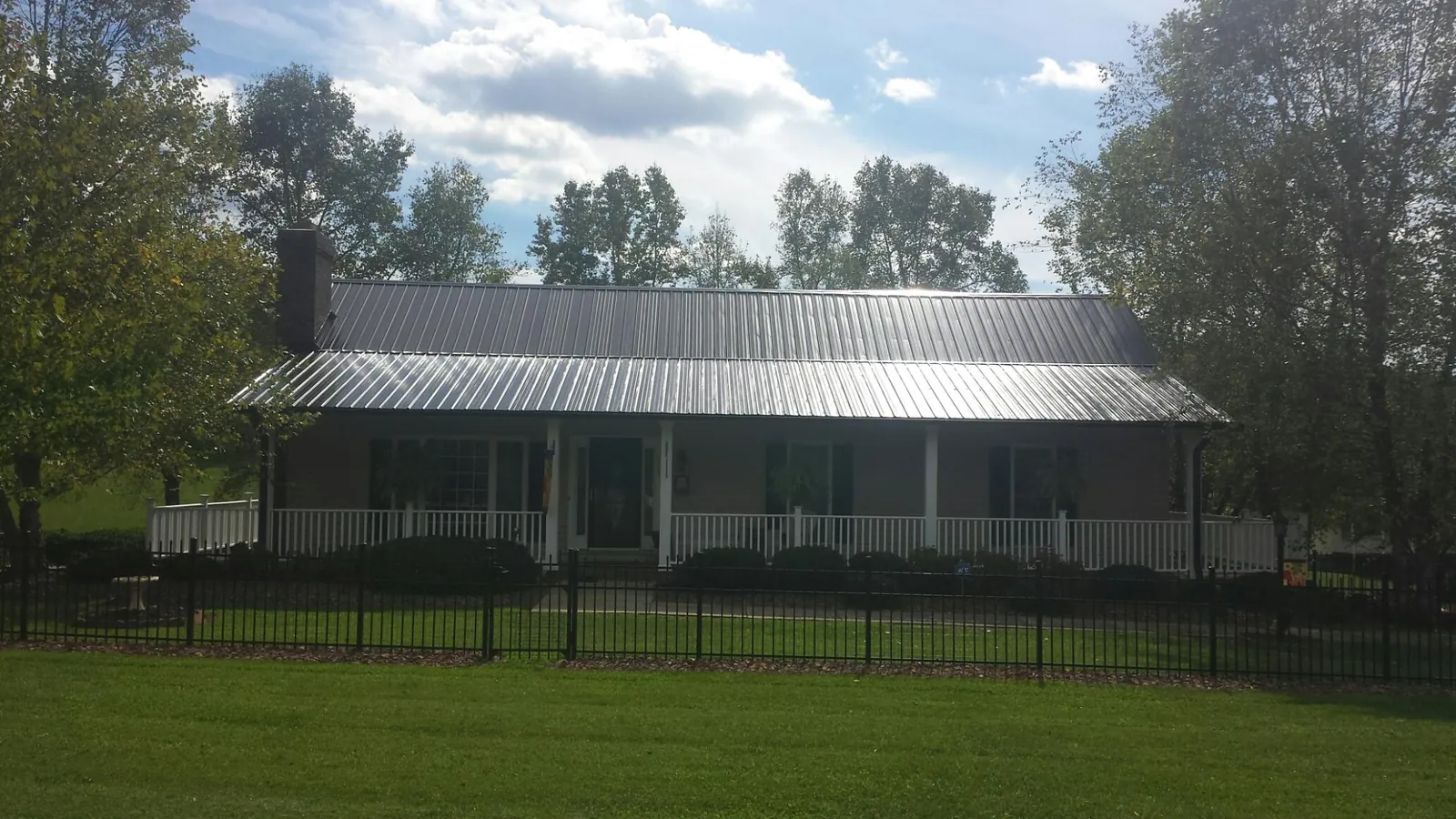 Gray metal roof on a brick ranch with a full width front porch — Gutter Guard Installation work by our crew in Sturtevant