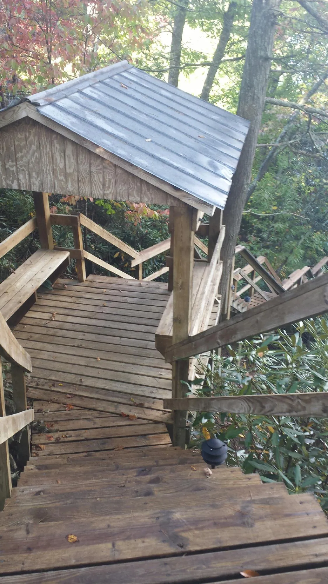 Metal roofed shelter over wooden steps on a wooded walkway — Skylight Repair & Installation work by our crew in Sturtevant